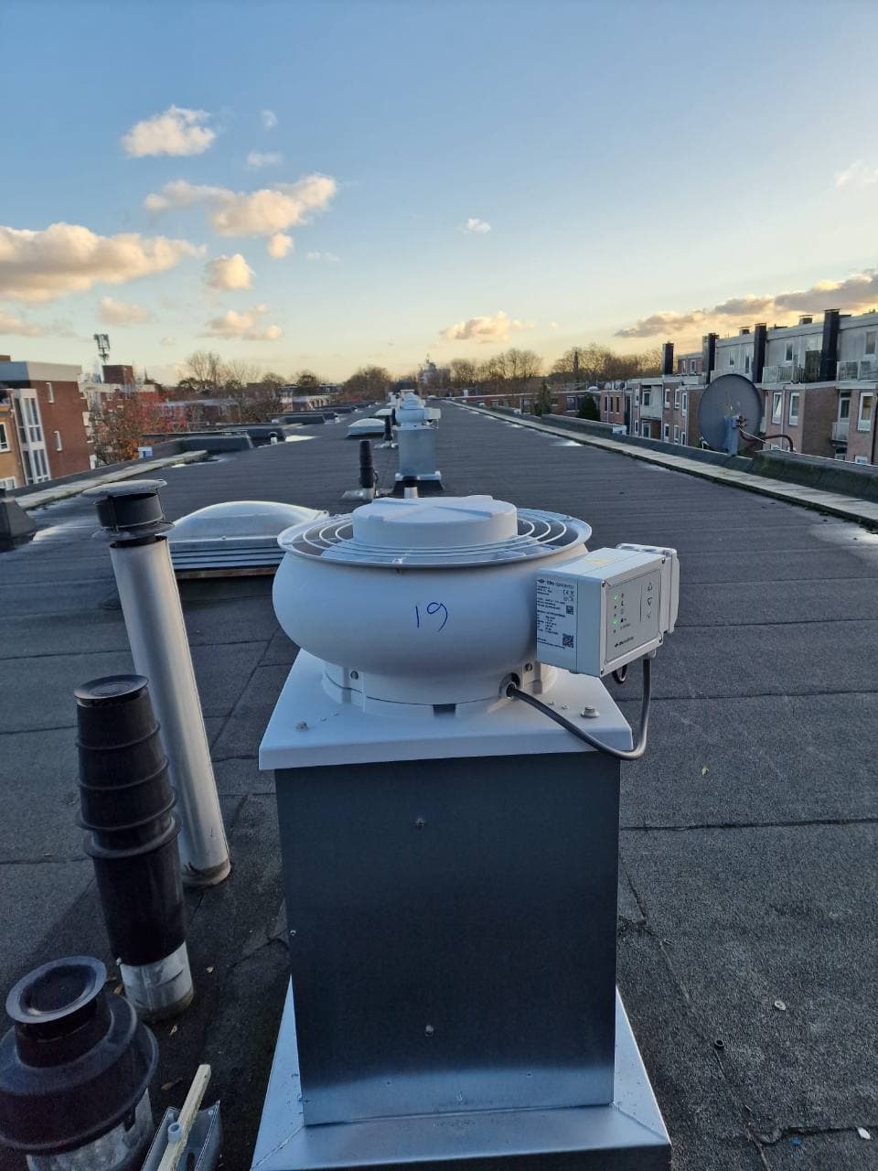 Nieuwe dakventilator met bediening op een wooncomplex in Amsterdam